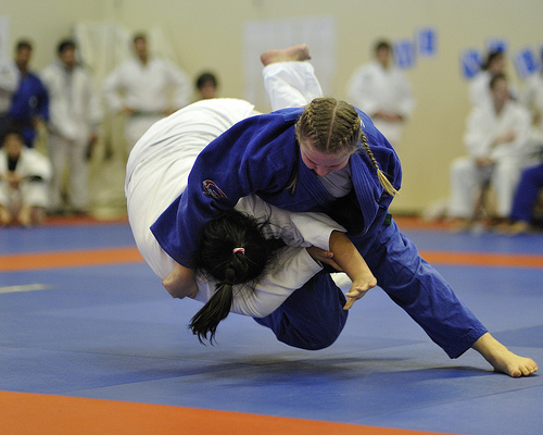 Two martial artists grappling towards a submission in a karate bout.